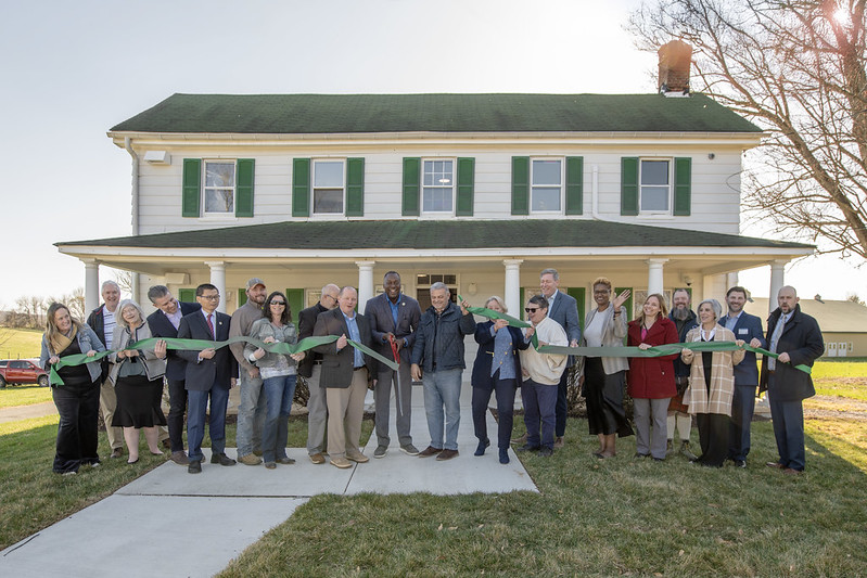 A photo of County Executive Calvin Ball out front of Hebb Hosue celebrating the cutting of the ribbon to officially open the County's new Office of Agriculture.