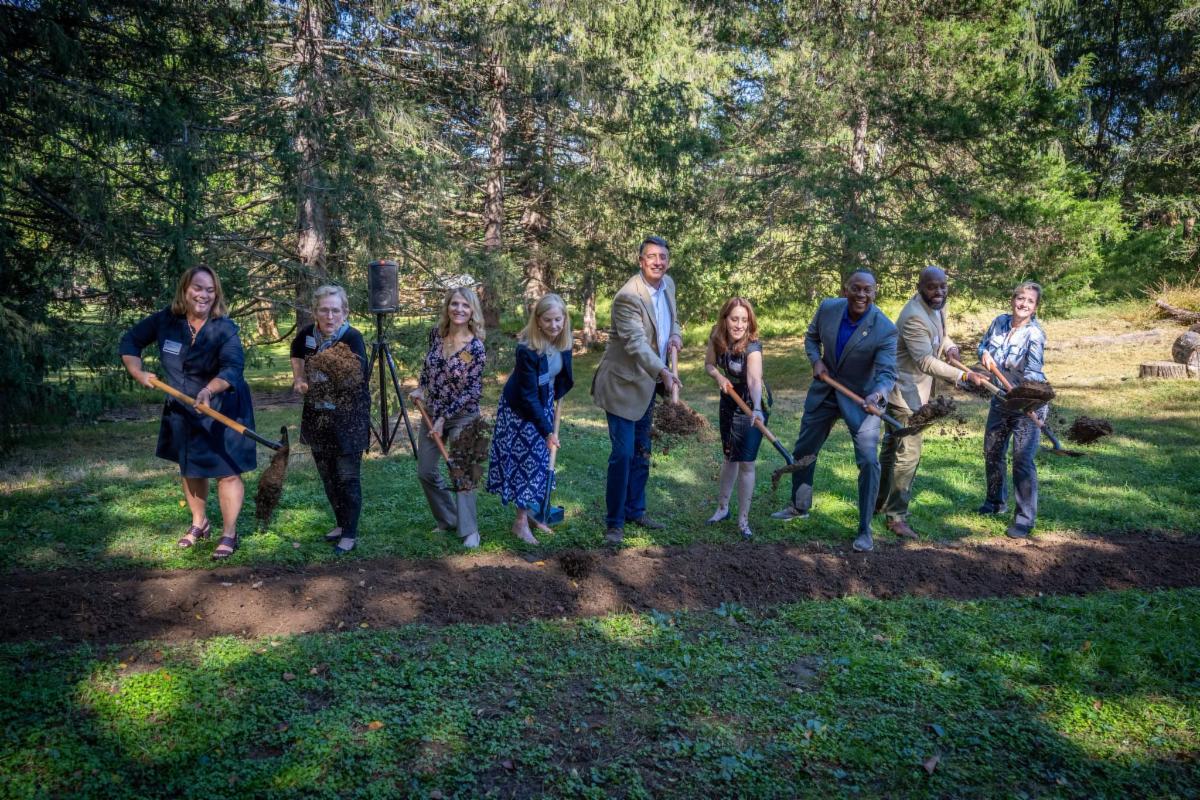 County Executive Calvin Ball and fellow elected officials and community members holding up shovels of dirt after breaking ground on The Howard County Conservancy's Pathways to Nature Project.