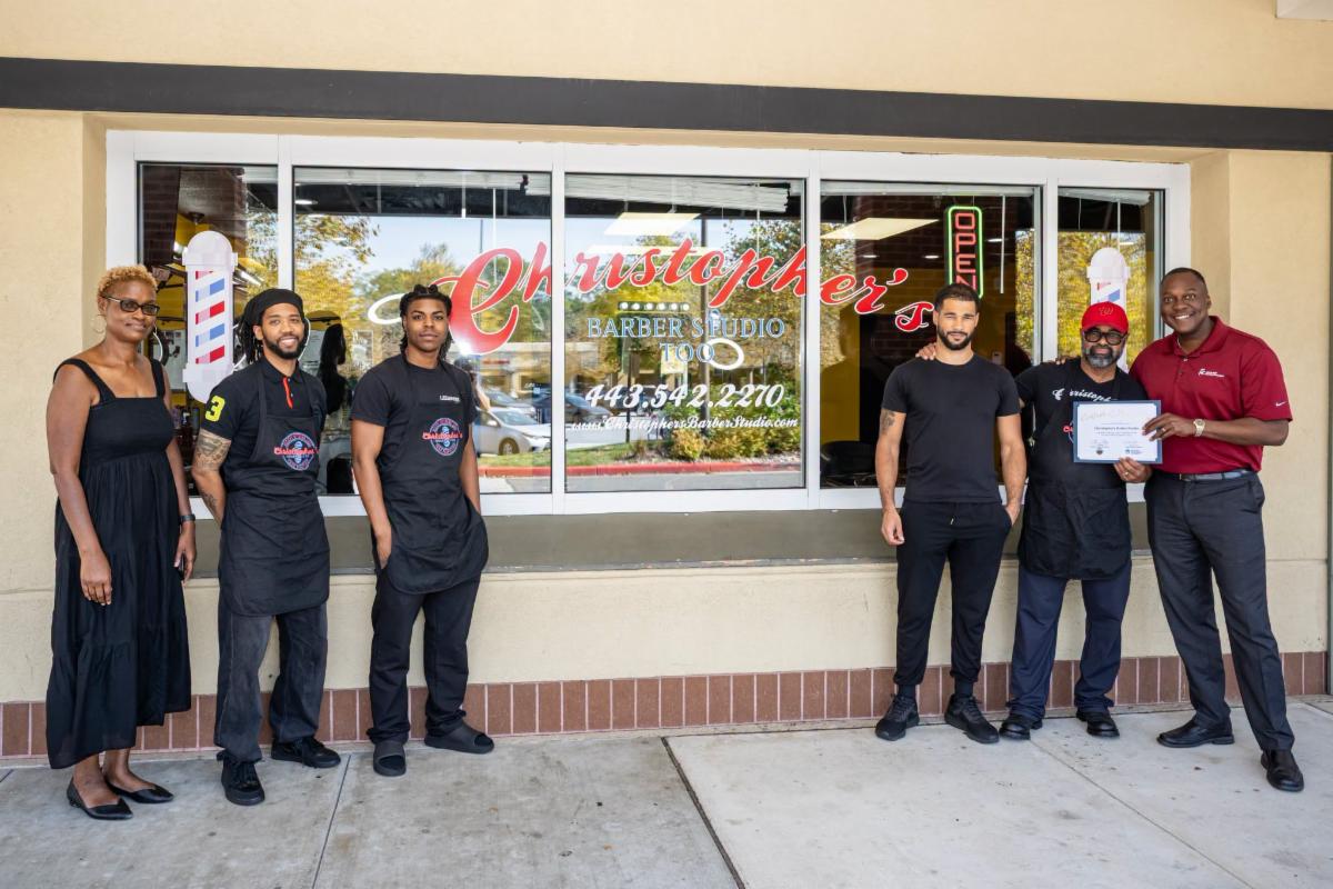 County Executive Calvin Ball posed for a photo outside Christopher's Barber Studio with Master Barber Christopher and staff members and Howard County Economic Development Authority CEO Jennifer Jones.