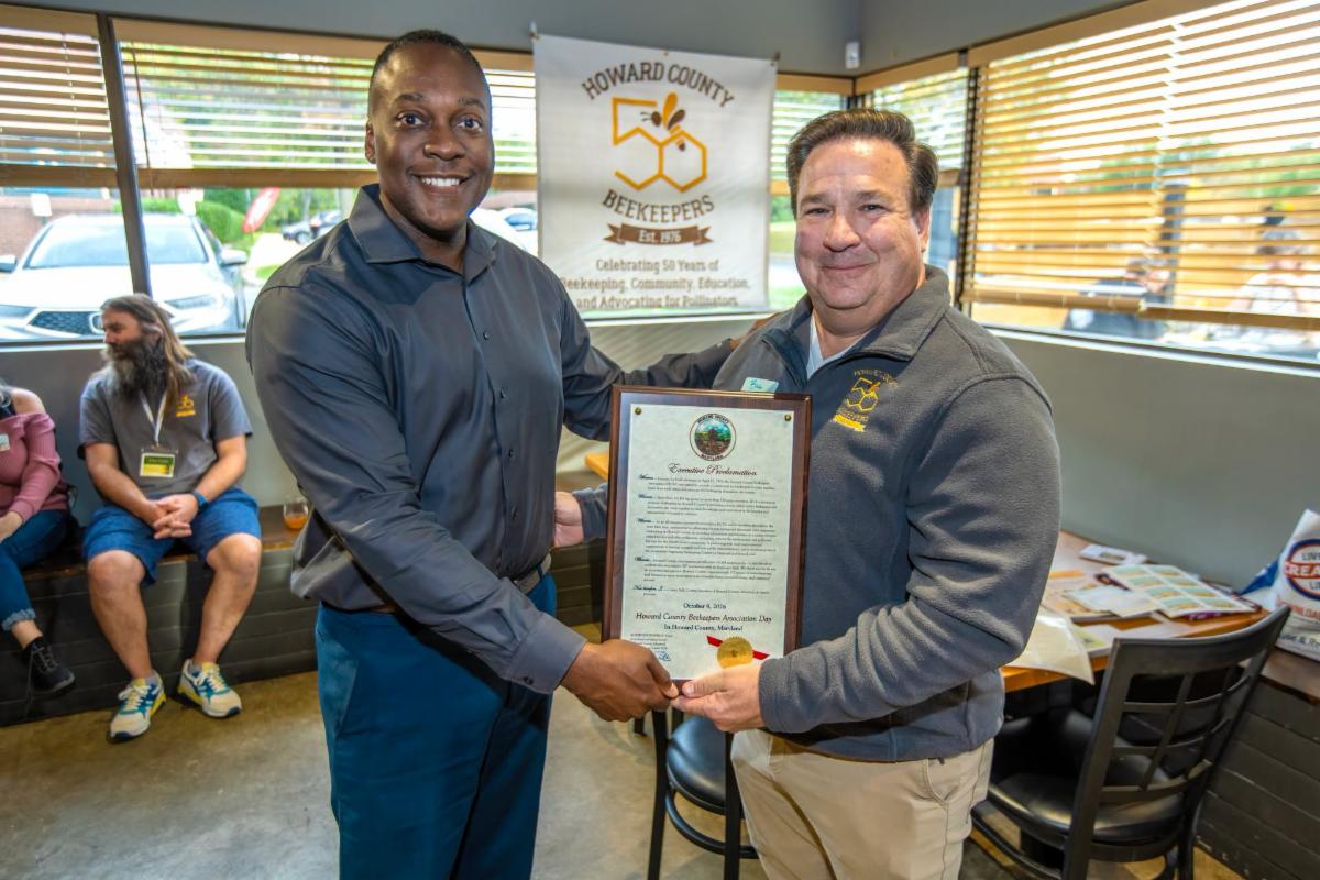 County Executive Calvin Ball posed for a photo with Howard County Beekeepers Association President Bill Glover while holding up a proclamation celebrating the organization's 50th anniversary.