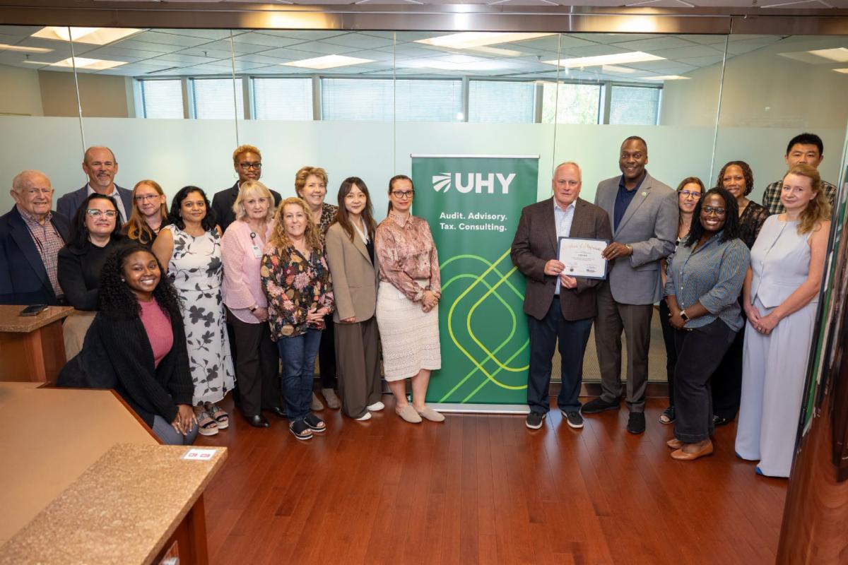 County Executive Calvin Ball posed for a photo inside UHY International's Columbia's office with staff members and Howard County Economic Development Authority CEO Jennifer Jones.