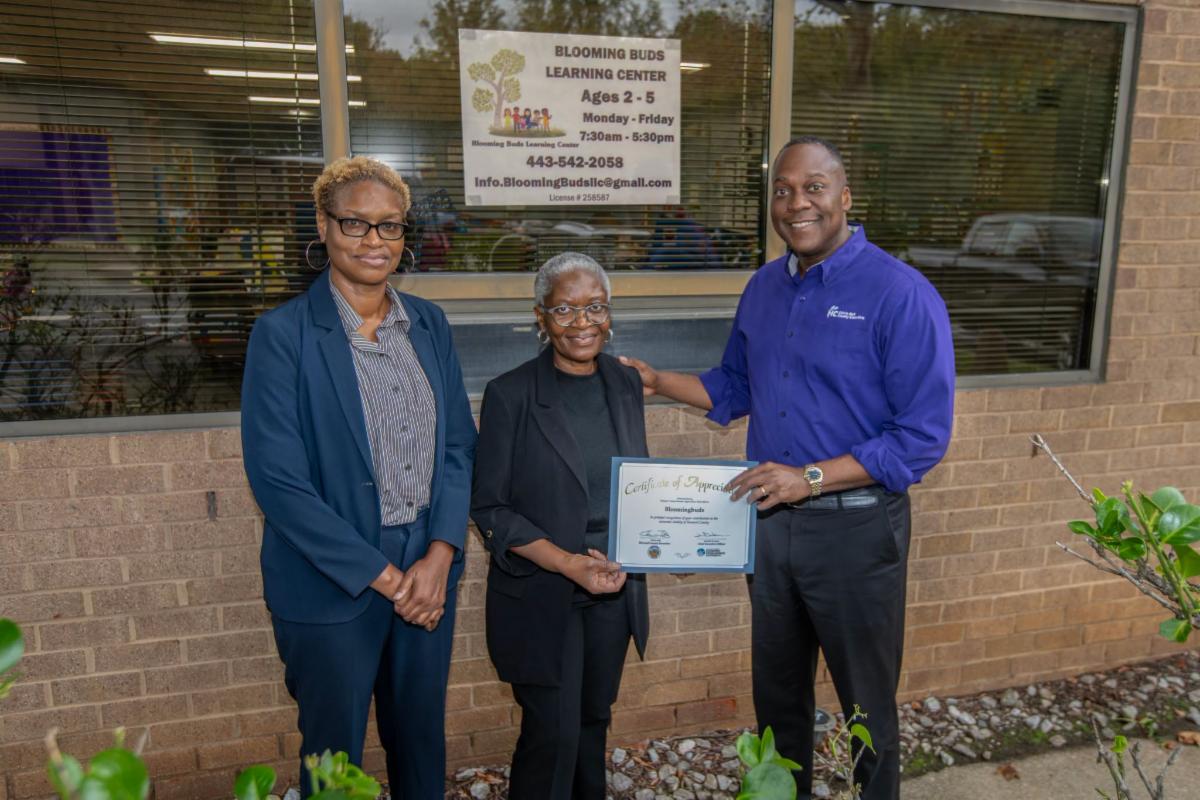 County Executive Calvin Ball posed outside of Blooming Buds Learning Center with its Director Victoria Doe Herring and Howard County Economic Development Authority CEO Jennifer Jones.