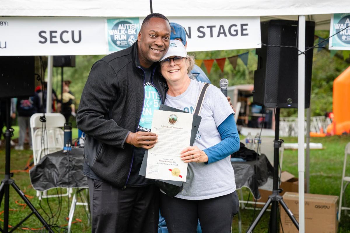 County Executive Calvin Ball at the Autism Society of Maryland's annual Every Step Counts Autism Walk and 5K Run posed for a photo with the Society's Executive Director Melissa Rosenberg holding up a proclamation proclaiming October 3, 2026 in her honor.