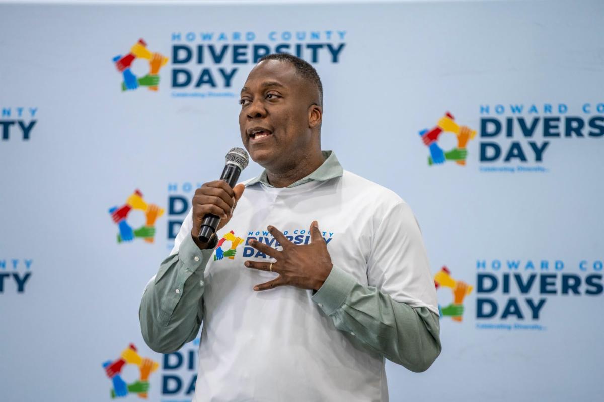County Executive Calvin Ball on stage with a microphone in hand speaking to attendees at Howard County Government's annual Diversity Day event. 