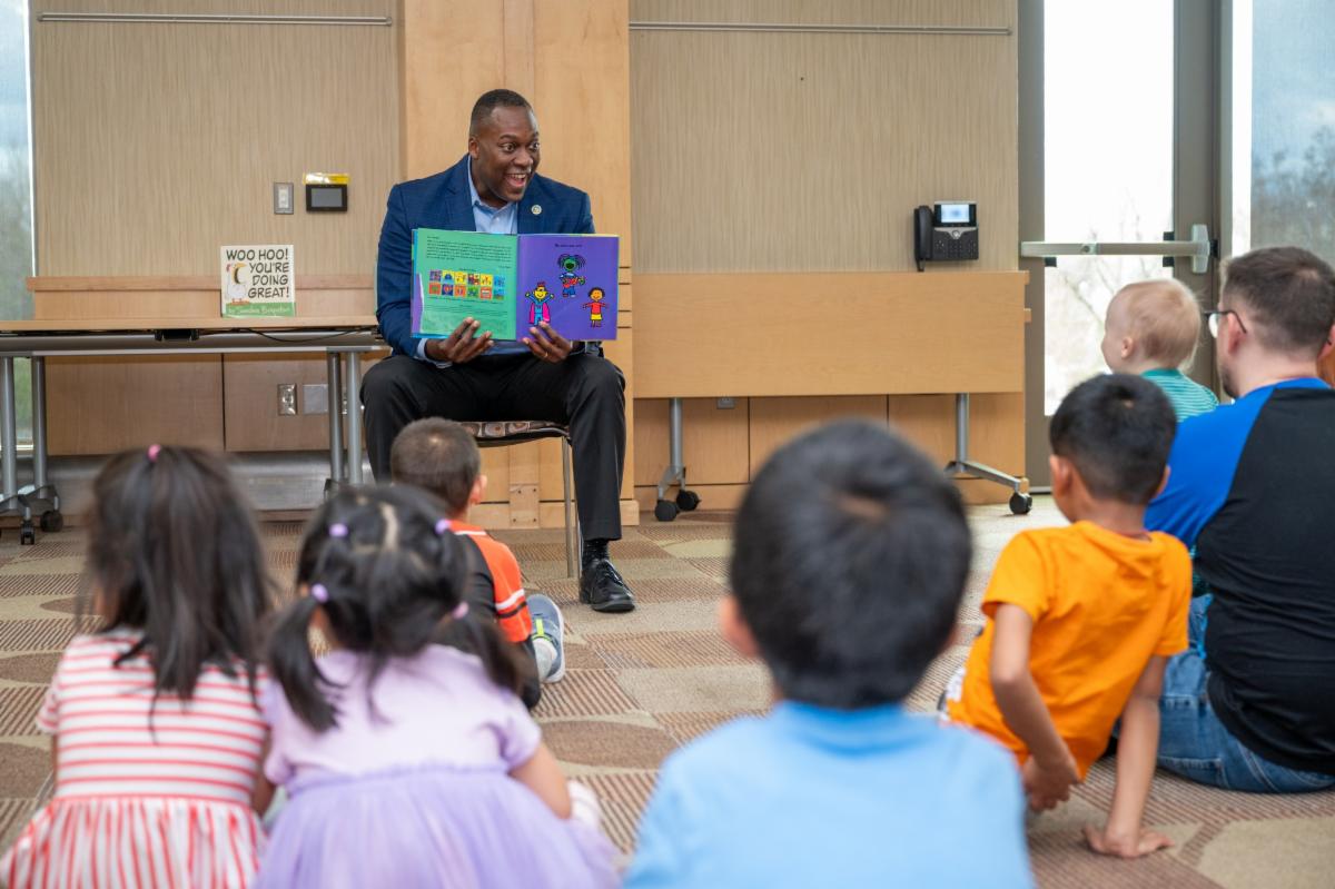 A photo of County Executive Calvin Ball reading a book to children.