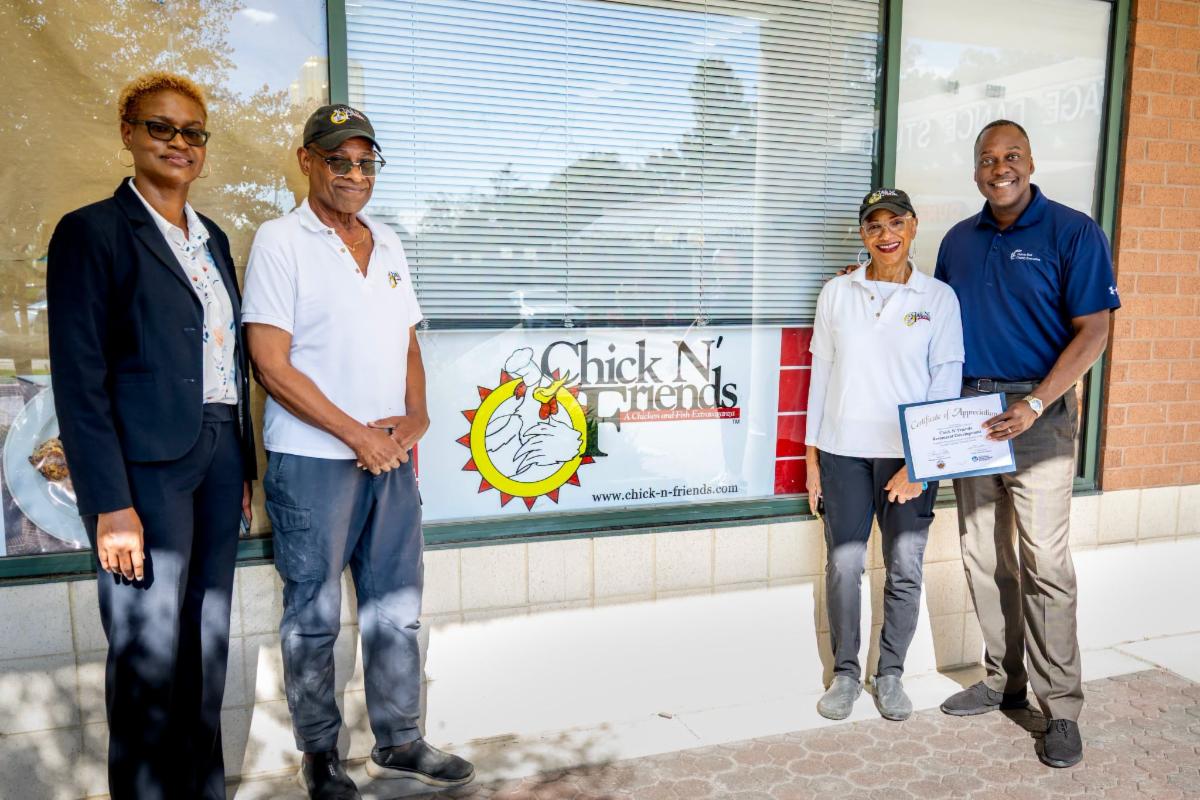 A photo of Calvin Ball and Jennifer Jones posing with the owners of Chick N Friends restaurant.