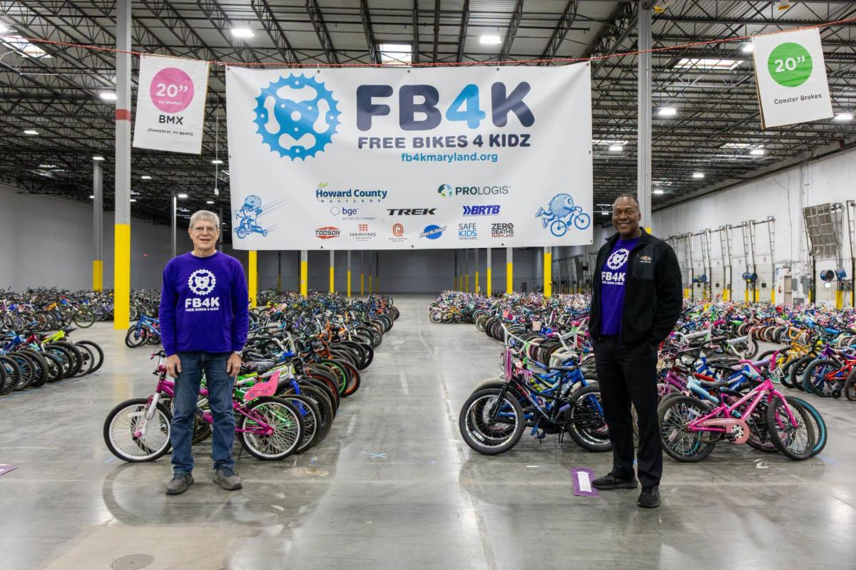 County Executive Calvin Ball posed with Free Bikes 4 Kidz Maryland's President Ted Cochra in front of rows of donated kid bikes at the organizations eighth annual collection day in 2026.
