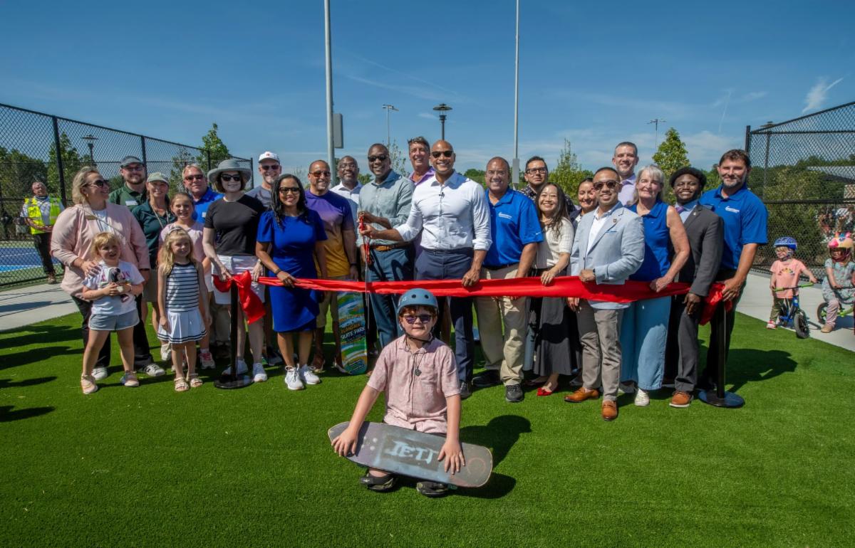 County Executive Calvin Ball posed with fellow elected officials Department of Recreation & Parks staff members and community members about to the cut the red ribbon to mark the opening of the amenities at Blandair Regional Park's west area.