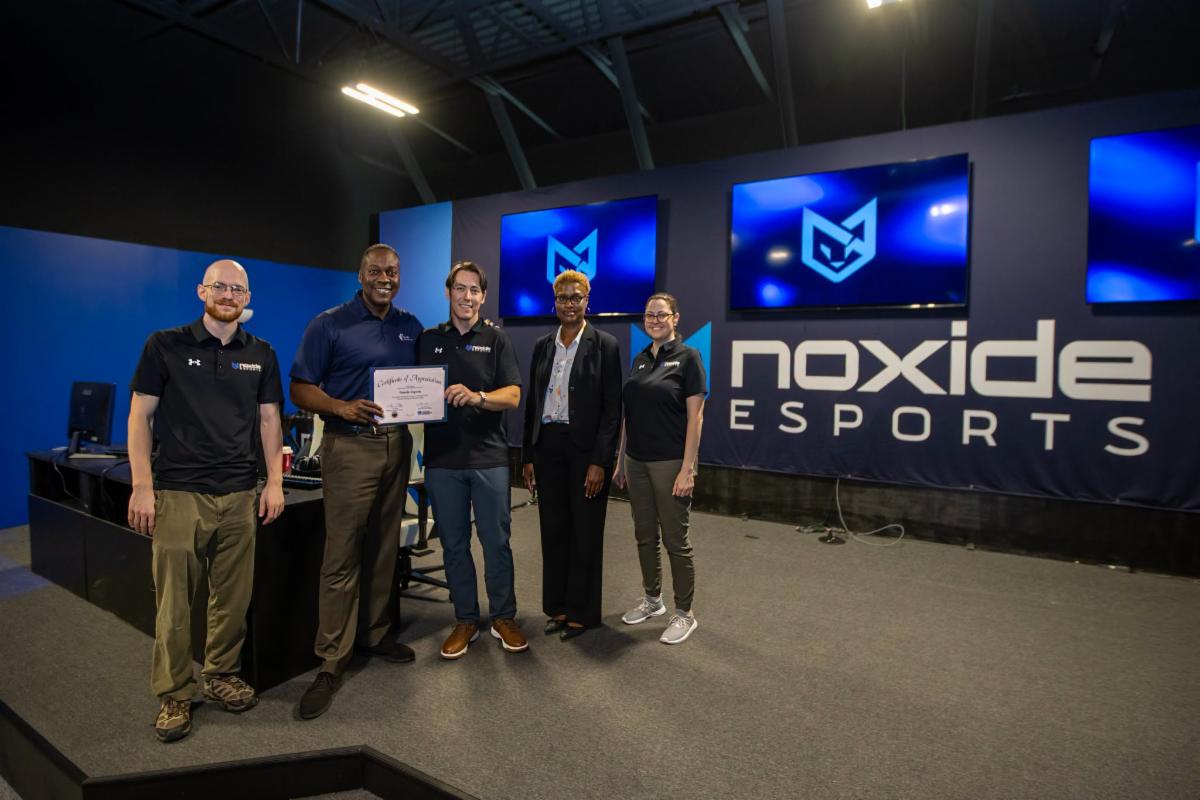 A photo of Calvin Ball and Jennifer Jones posing with the owners of Noxide Esports