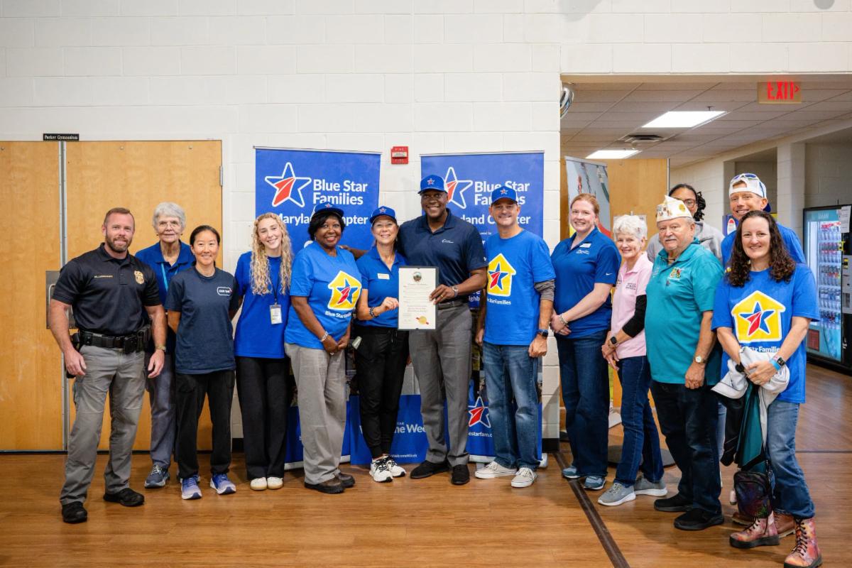 County Executive Calvin Ball posed inside a gymnasium with members of the Blue Star Families Maryland Chapter.