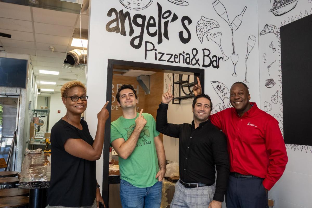 County Executive Calvin Ball posed for a photo inside Angeli's Pizzeria & Bar's new Howard County location with Howard County Economic Development Authority CEO Jennifer Jones and Juniet Ozturk and his family member.