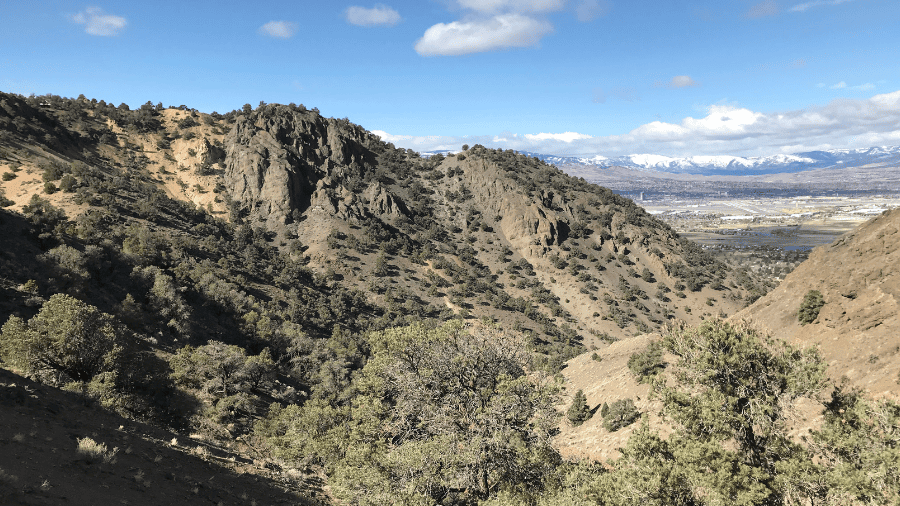 A rugged mountain landscape with scattered trees on dry slopes.