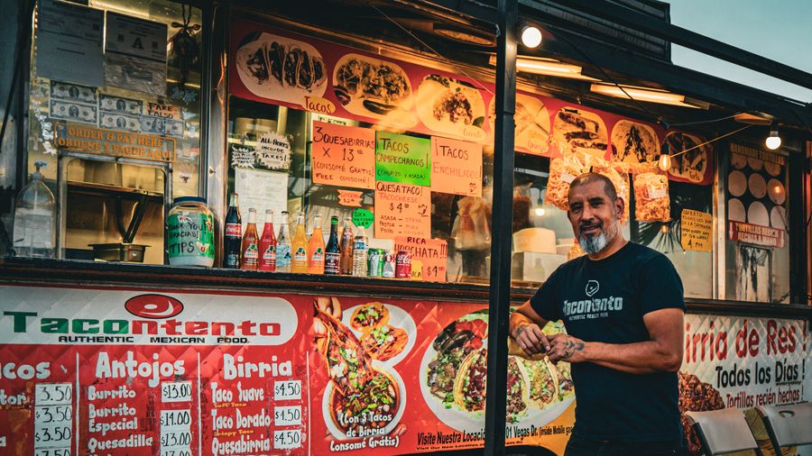 A man poses next to a truck featuring images of food.