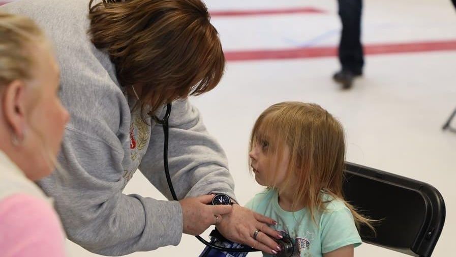 A child from Tonopah gets a medical exam by a woman who is checking vitals.