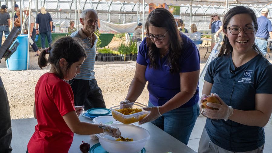 Smiling Extension staff and community members gather around a table to enjoy fresh mango salsa together.