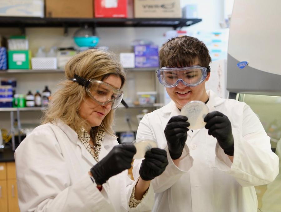 Patricia Santos and a student examining an object in a lab.