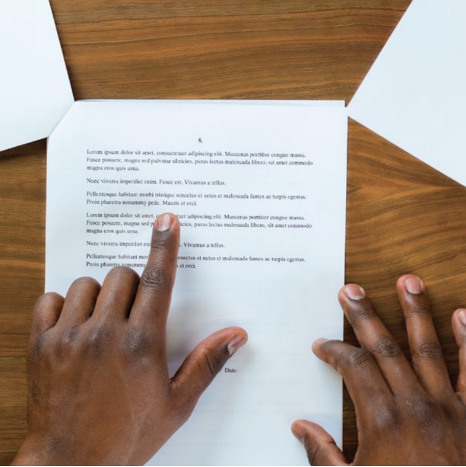 Hands point at a piece of paper on a table