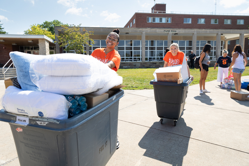 Goon squad members assisting students with moving bins. 