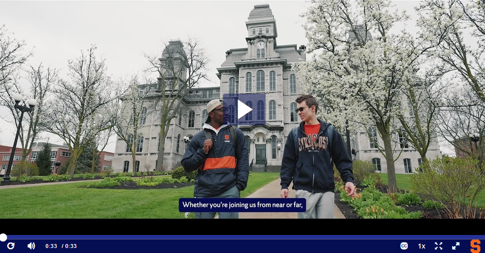 two students walking on campus with closed captioning of a video when the play button is pressed