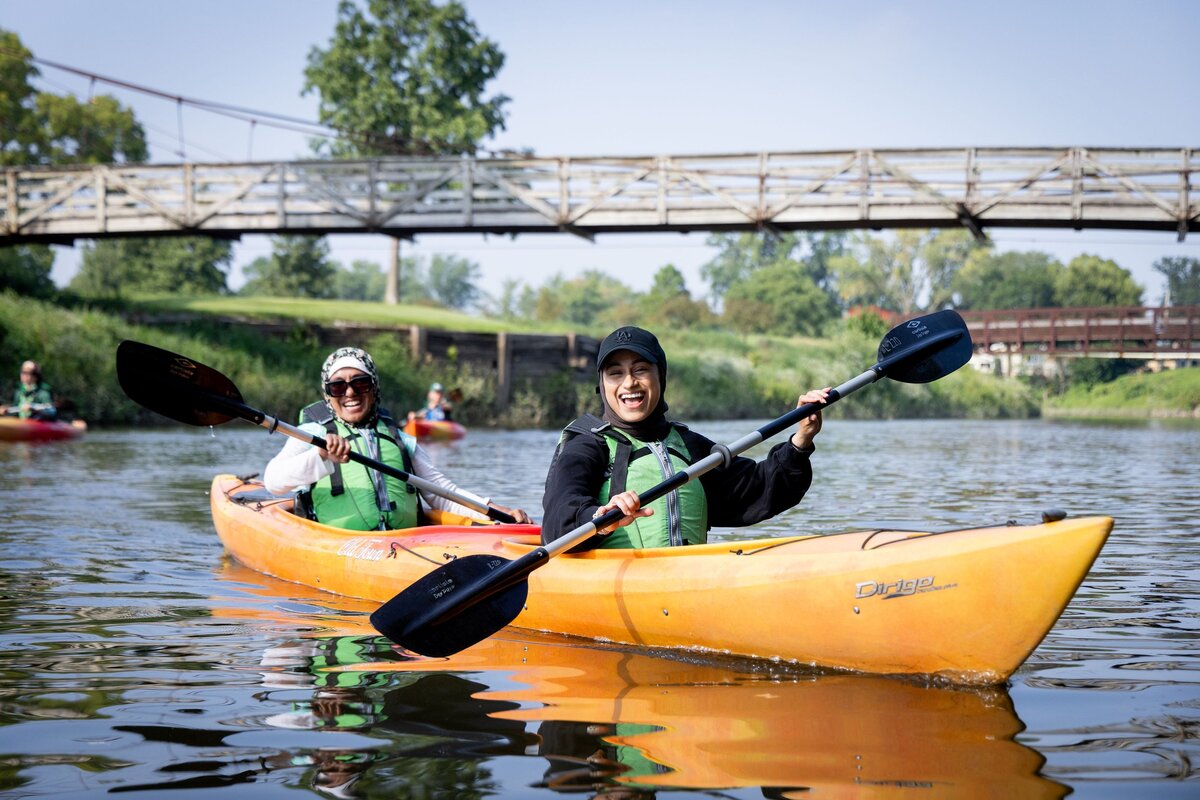 Two women paddle a kayak on a sunny day