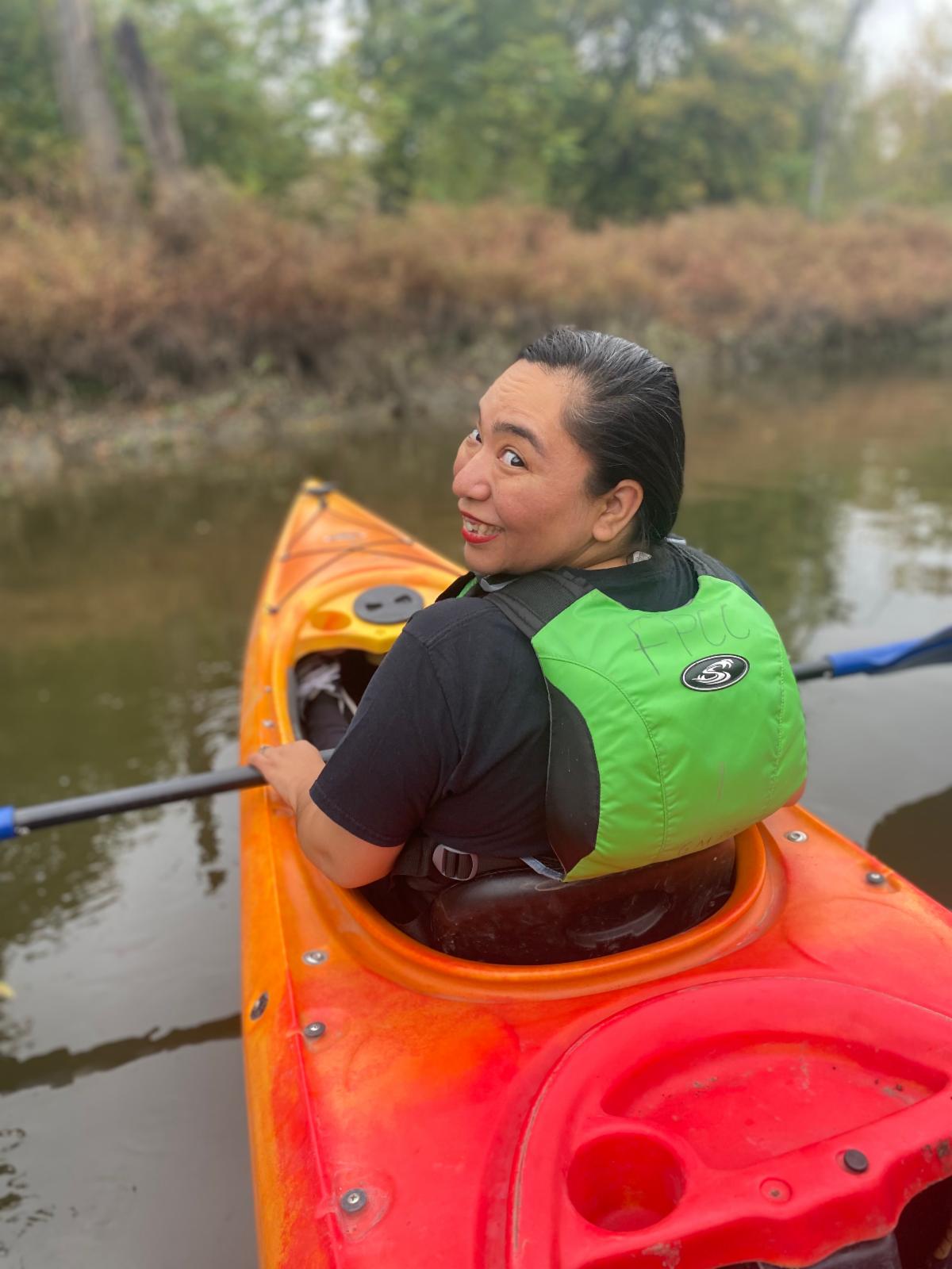 Griselda Piedra turns and smiles while kayaking on a river in fall