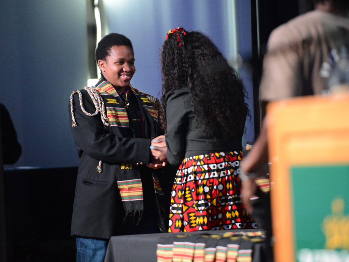 A Black student walks across the stage and shakes hands at the podium at the Black Futures Celebration 2026
