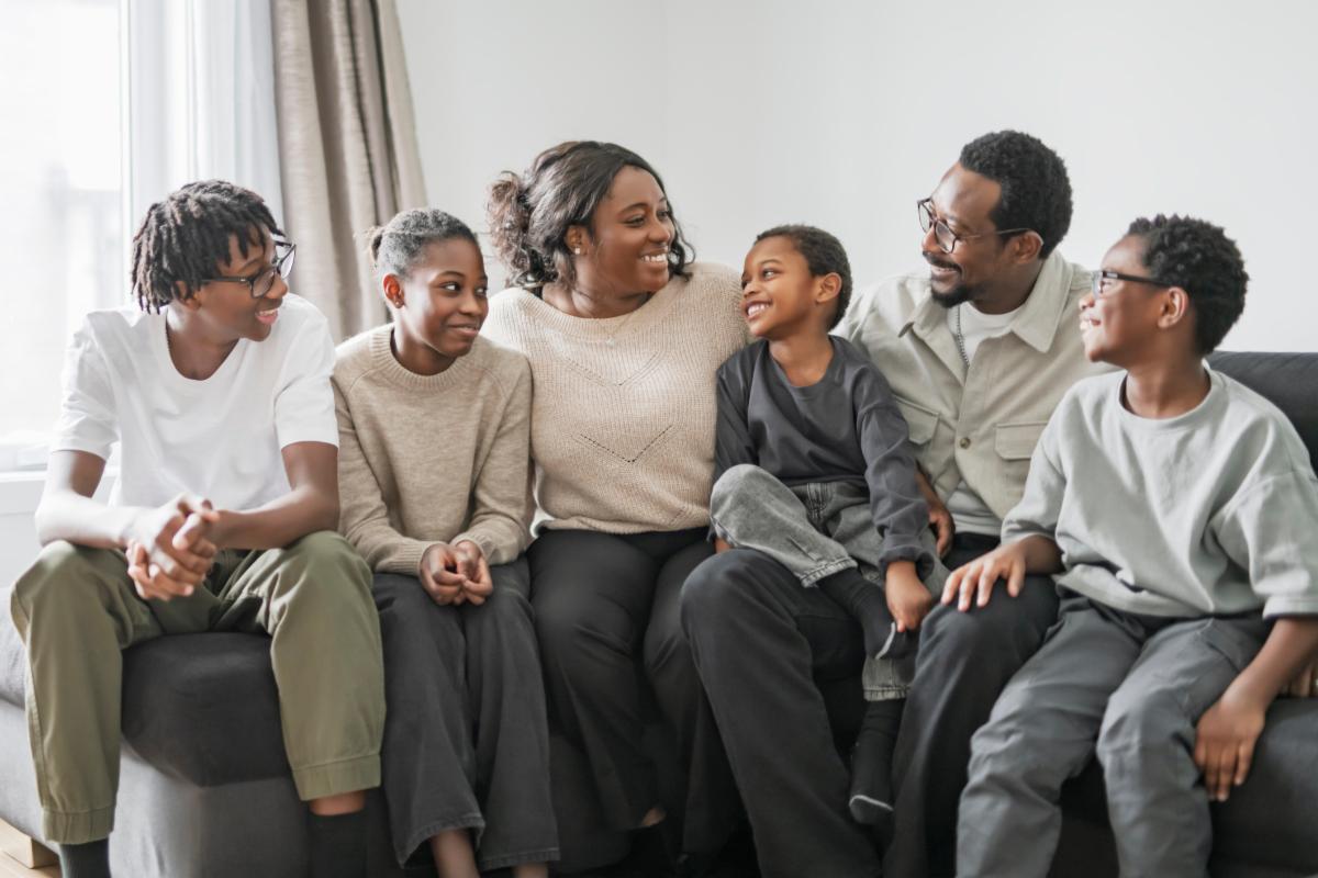 A Portrait of happy black family sitting at home. Smiling couple with kids sitting on couch.