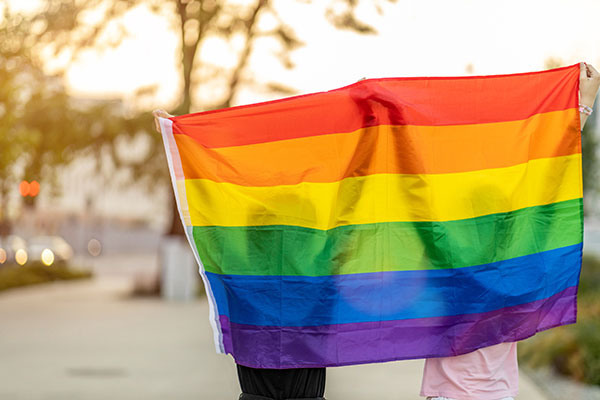 Two people raising a rainbow flag - celebrate LGBTQ+ festivities at our Saugatuck bed and breakfast