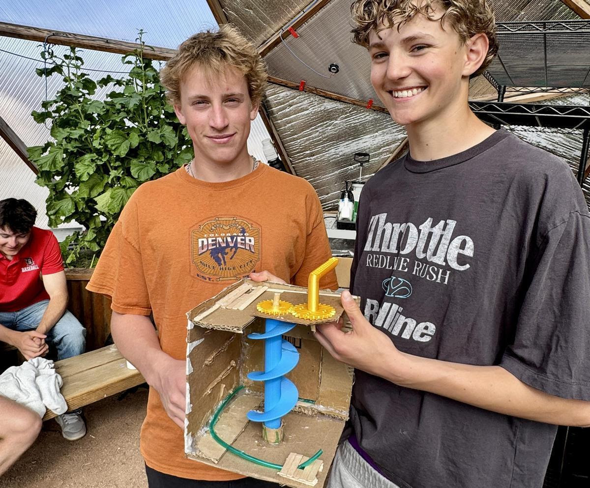 Two students hold up their prototype