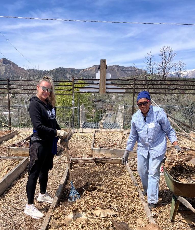 Two volunteers taking leaf mulch off of a raised bed