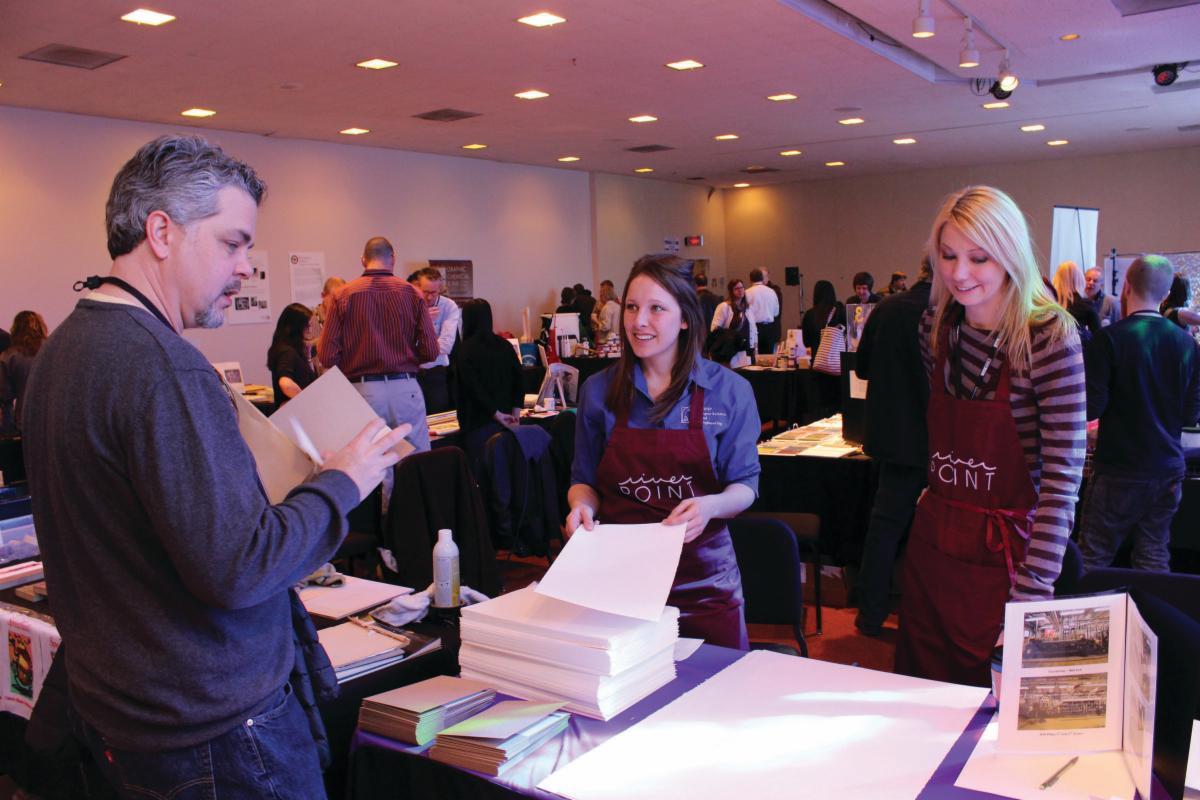Two UWSP women display RiverPoint Paper at conference to a potential customer