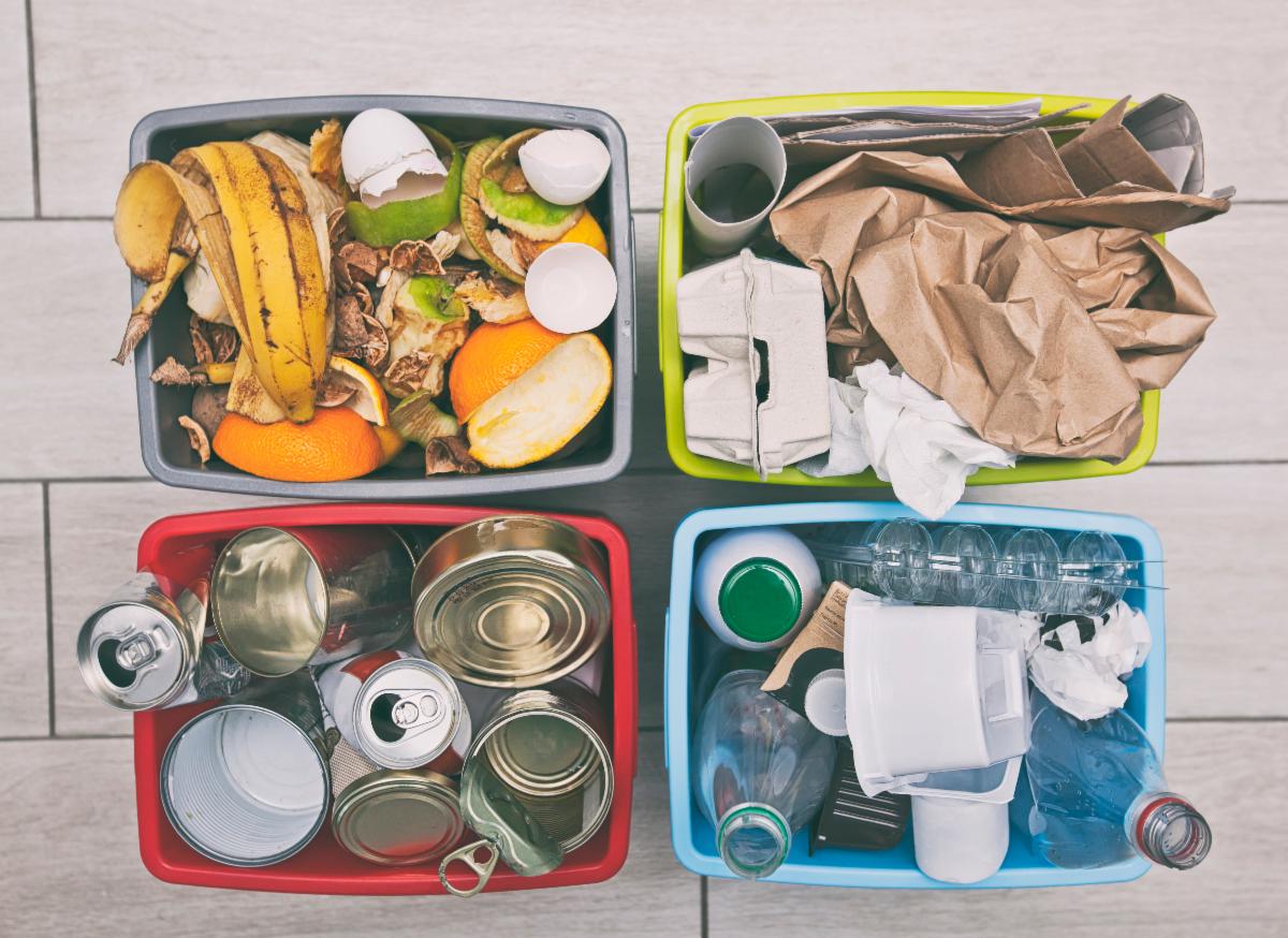 Four recycling bins hold four different types of material: Plastic, metal, paper and food waste.