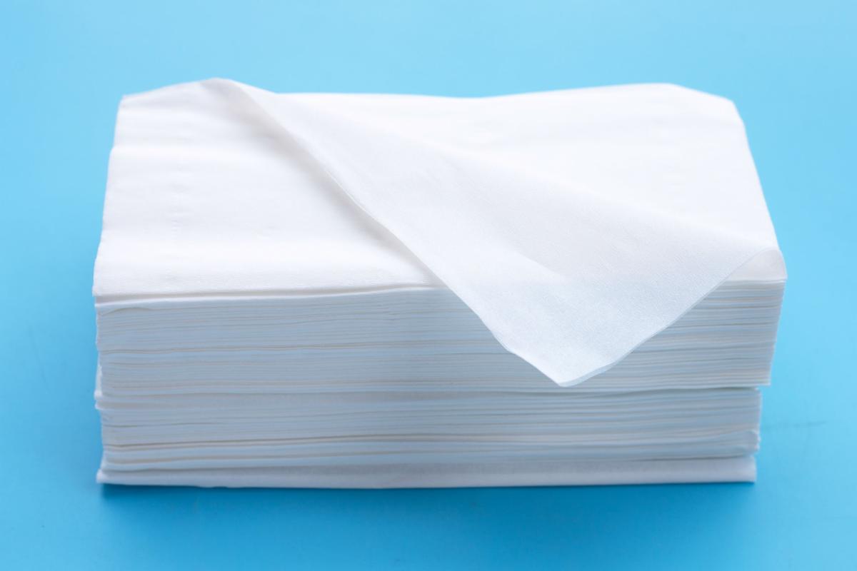 A stack of facial tissues stands against a blue background.