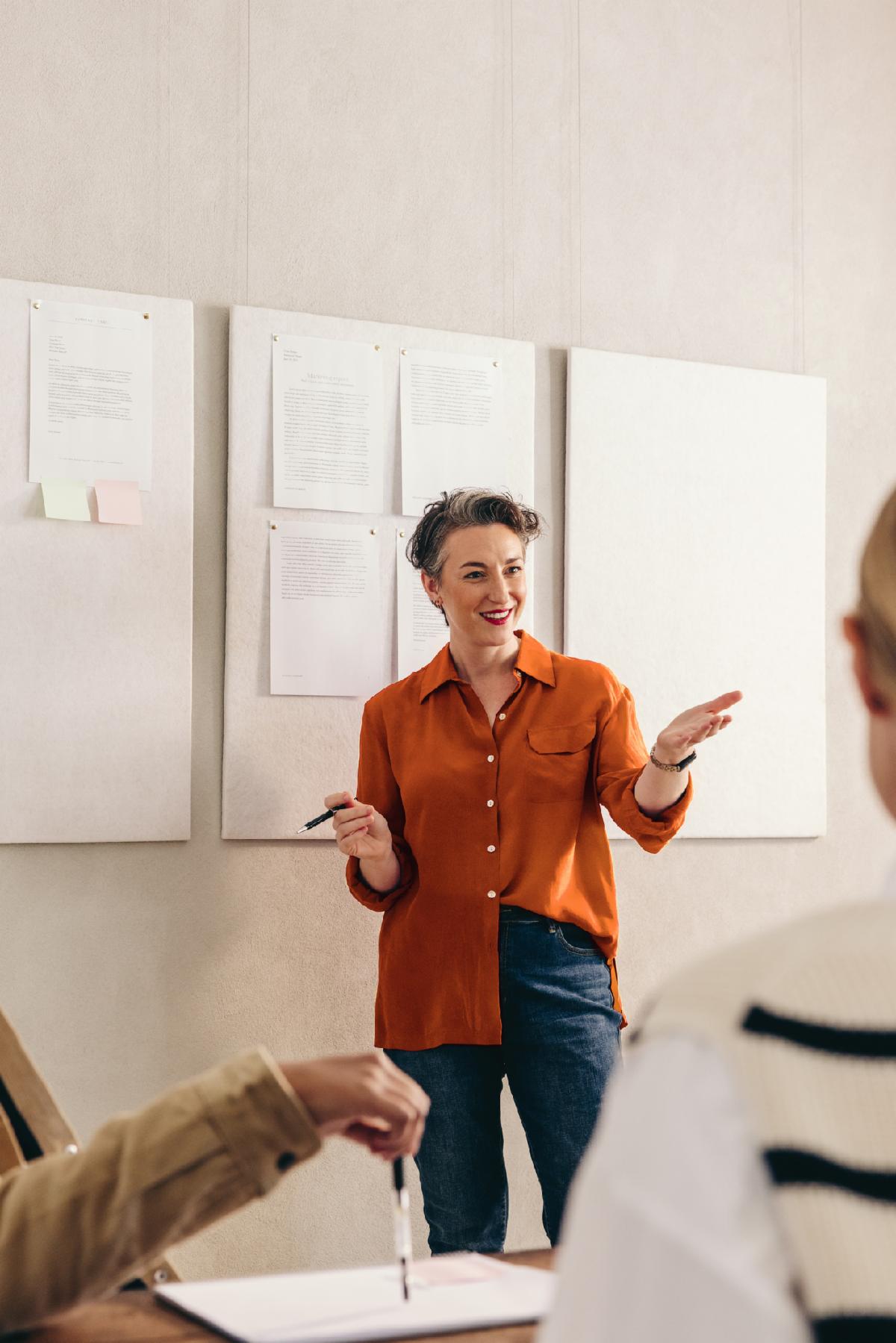 Cheerful businesswoman pitching her idea to her team during a meeting. Happy team leader having a discussion with her colleagues. Group of creative businesspeople working together in an office.