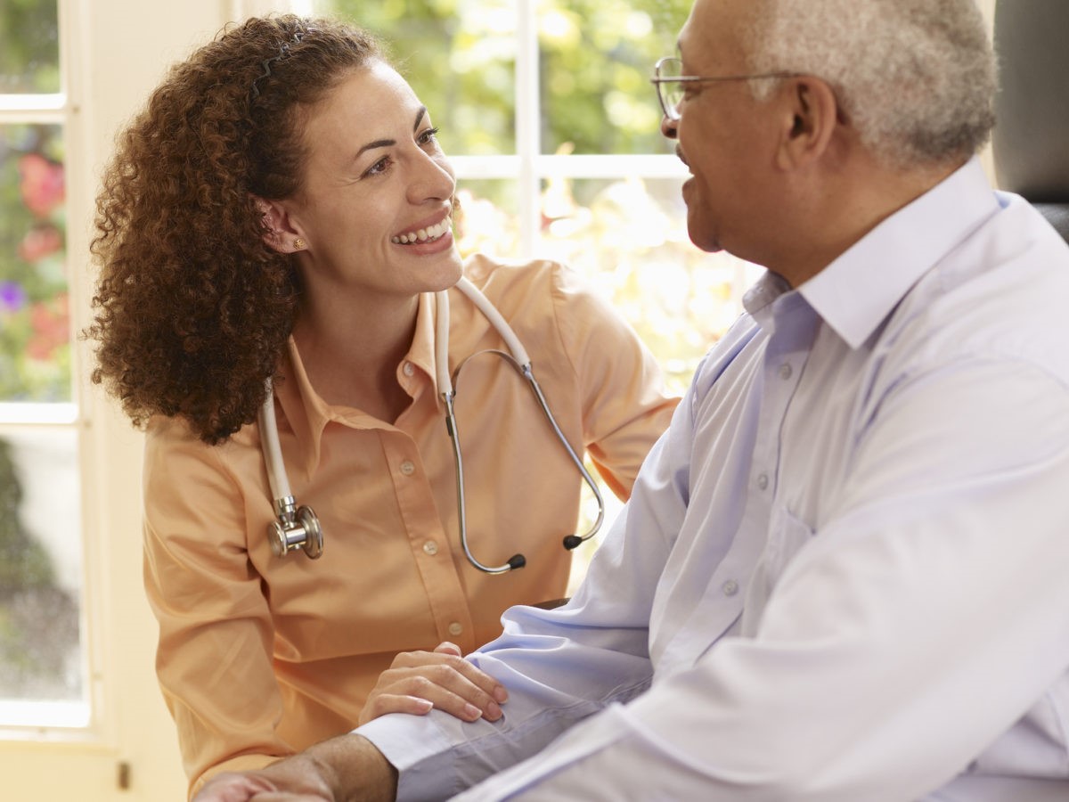A health professional speaks with an older adult in a home setting, providing personalized care and support.