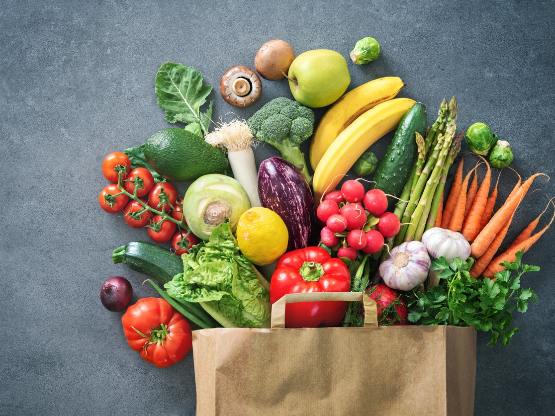 A shopping bag filled with fresh fruits and vegetables.
