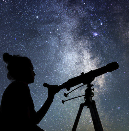 A silhouette of a woman using a telescope, and a starry sky in the background.