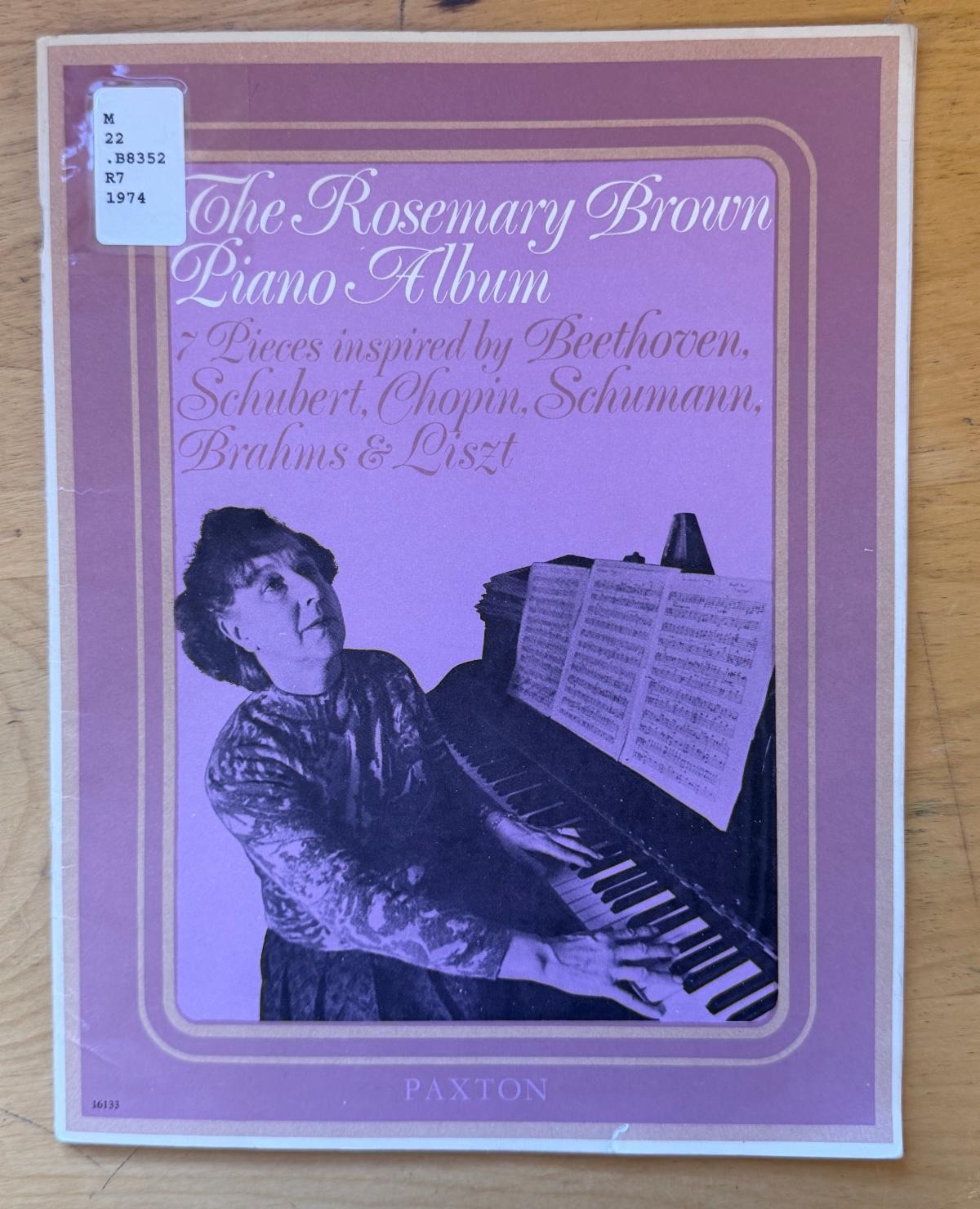Photo of a songbook showing a woman sitting at a piano