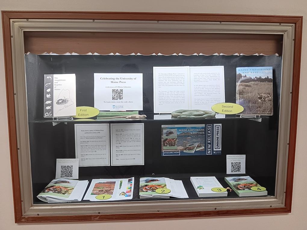 Photo of a display cabinet containing items pertaining to the UMaine Press
