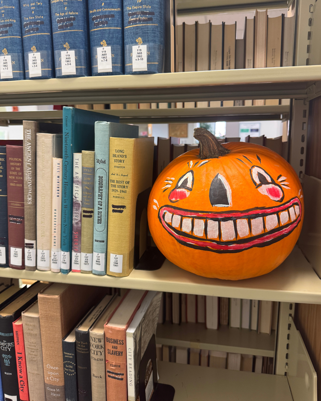 A painted pumpkin sitting on a bookshelf