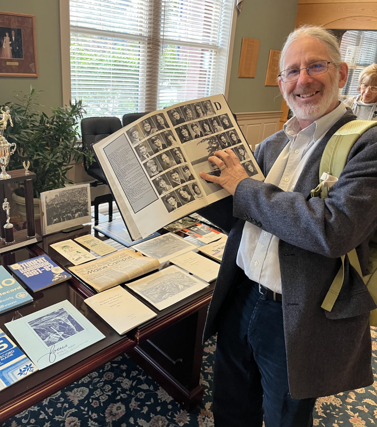 Photo of a man smiling and holding up a book showing several photographs