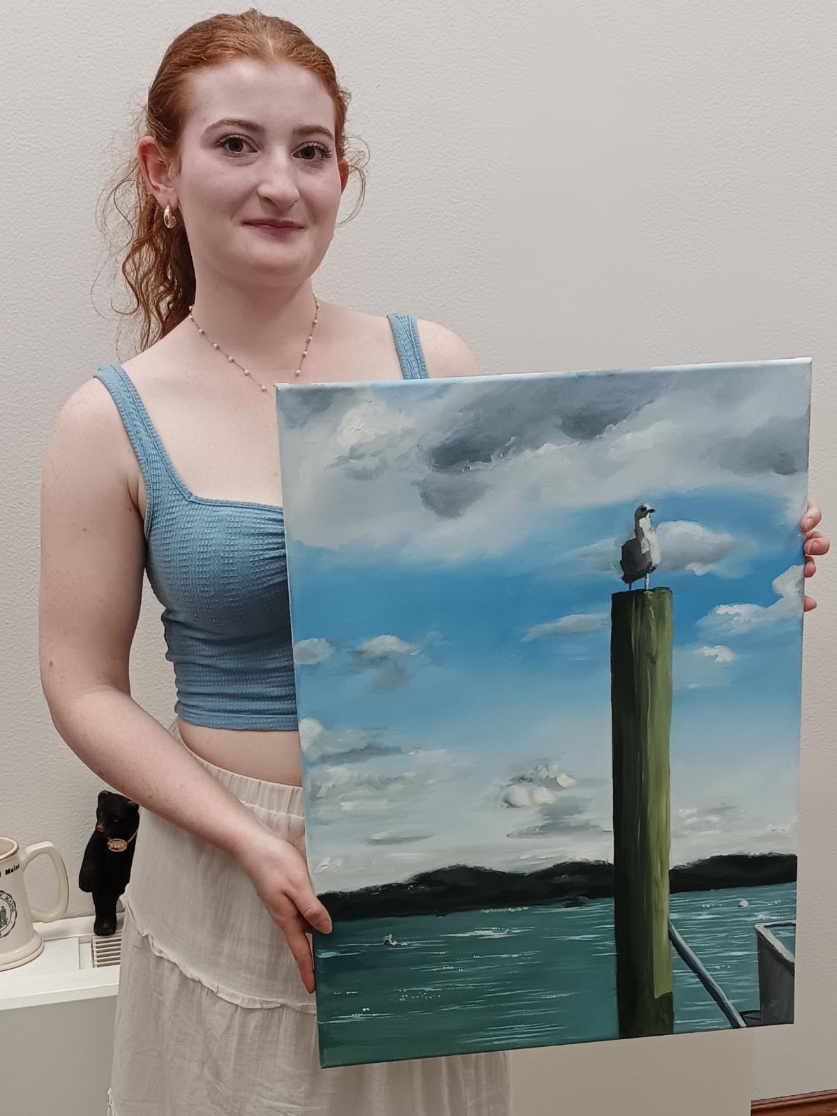 Photo of Alexandra Boman and her painting A Quiet Perch depicting a seagull on a wooden pole