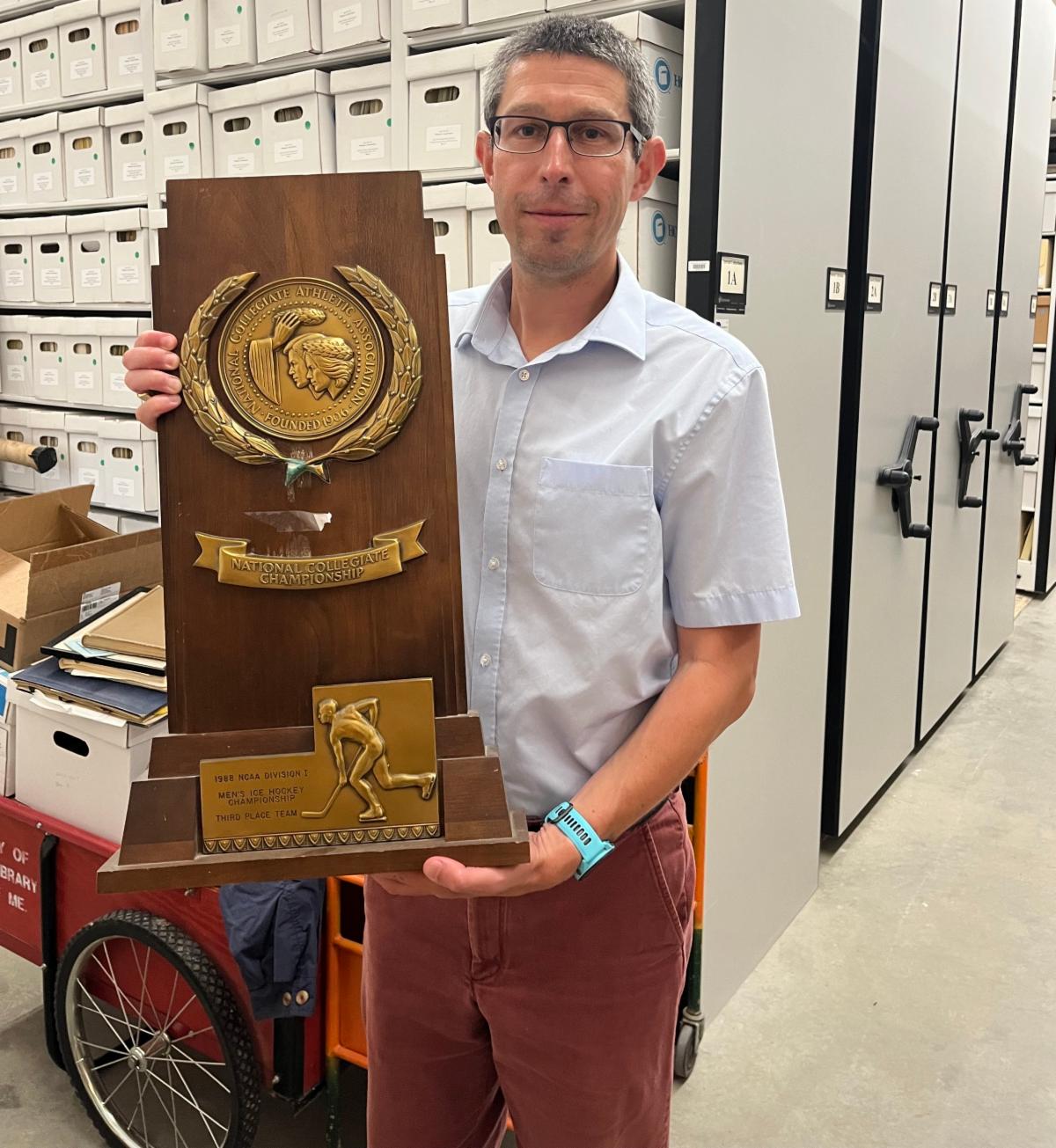 Photo of SCP staff member Matthew Revitt holding a hockey hall of fame trophy