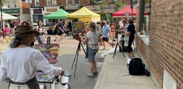 A side view of 4 artists painting a the farmers market at the Plein Air Event in 2023