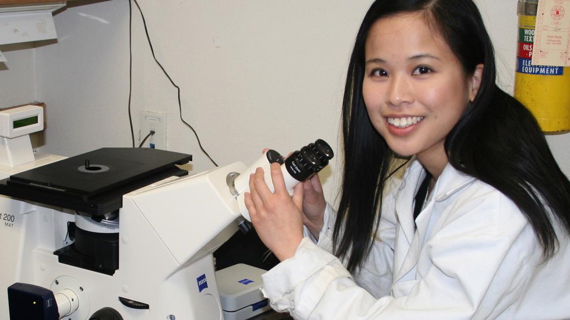 Female student looking through a microscope