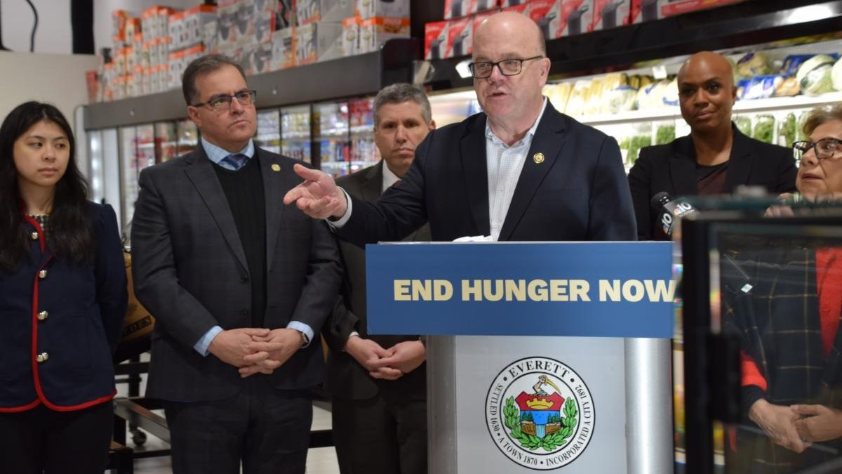 Jim McGovern speaks at a podium displaying a sign that reads “End Hunger Now.”