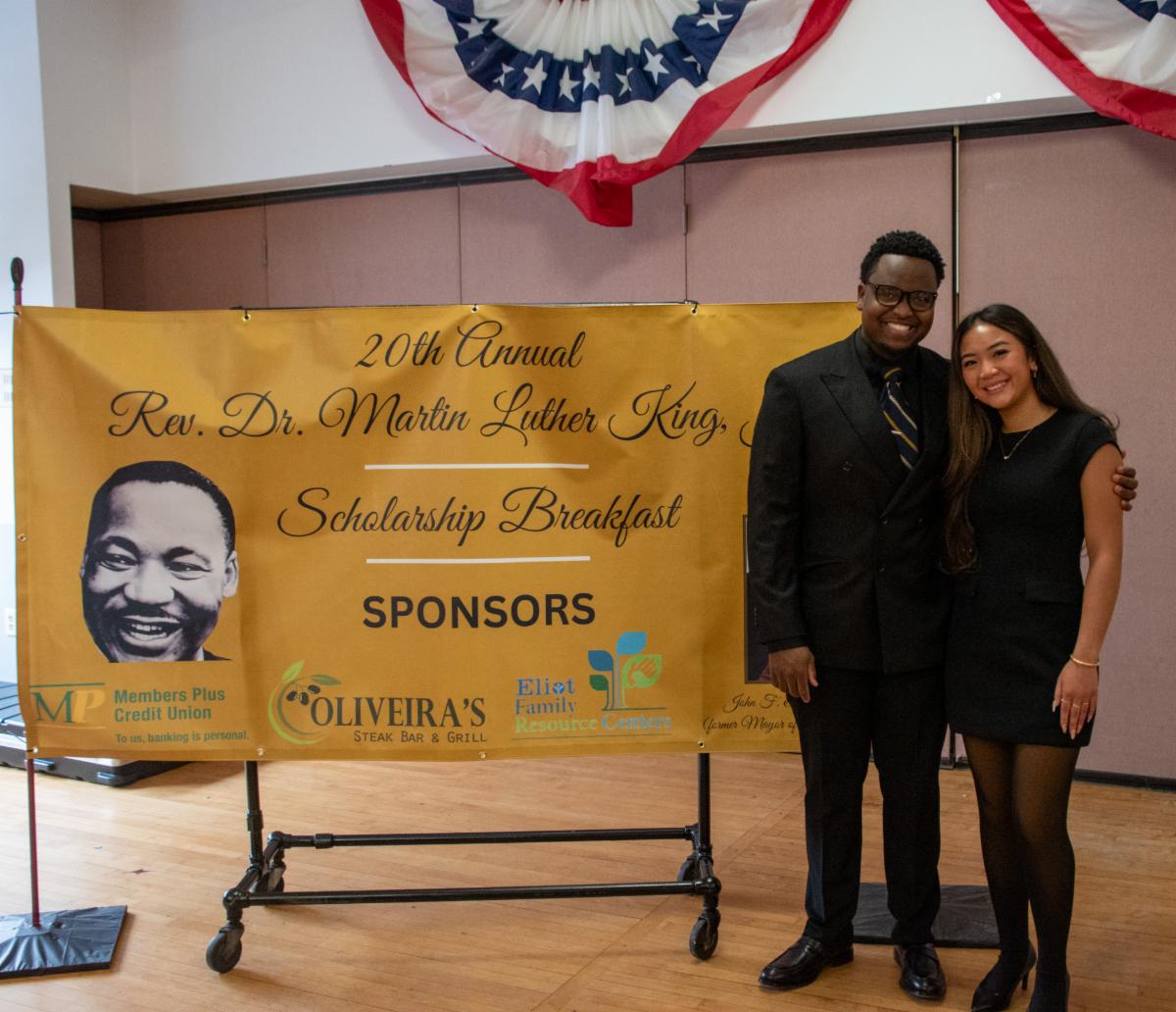 Scholarship recipients Danica Pham and Trevon Carrington stand beside the Martin Luther King Jr. Scholarship Breakfast banner.