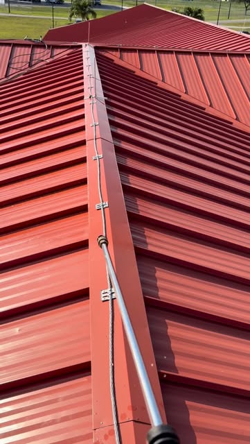 Red metal roof mid-cleaning, with a bright clean strip beside the weathered section