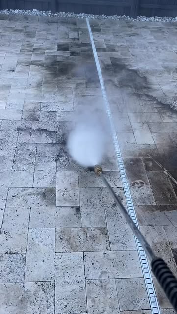 Travertine pavers mid-cleaning, the cleaned section much lighter than the dirty one