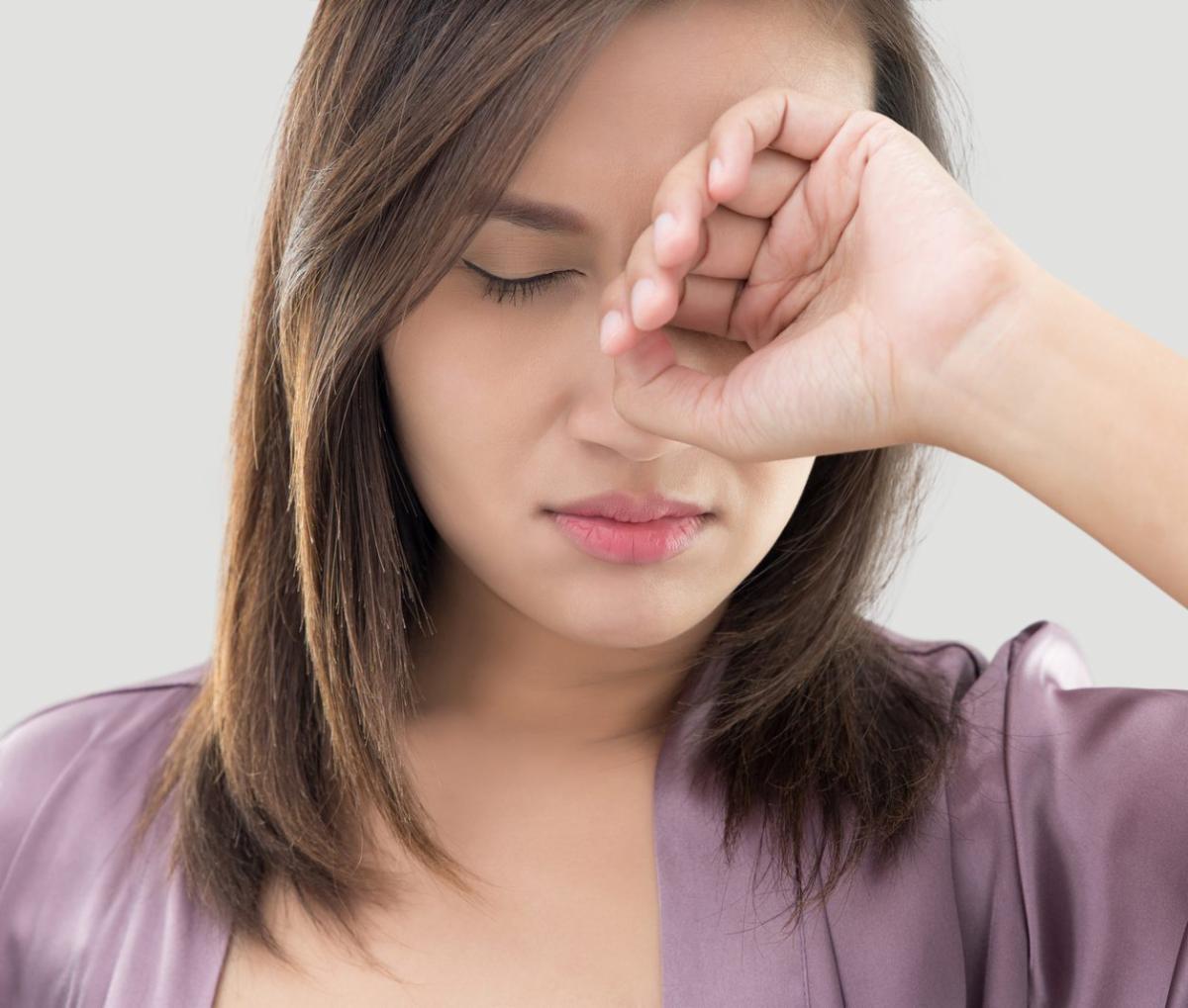 A photo of a woman rubbing her eyes.